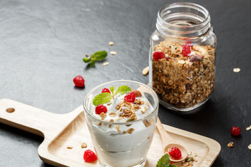 Greek yogurt in a glass with spoons on black stone slab