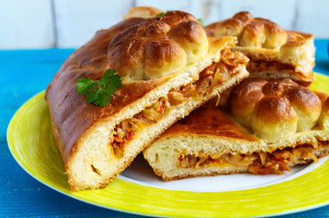 Homemade pie with cabbage chopped pieces on a blue background. Close up