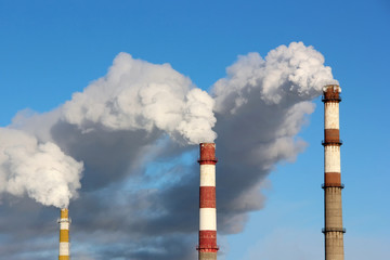 Dense smoke burst from the three factory chimneys.