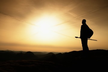 Sunny fall morning. Hiker is standing on peak of rocky mountain