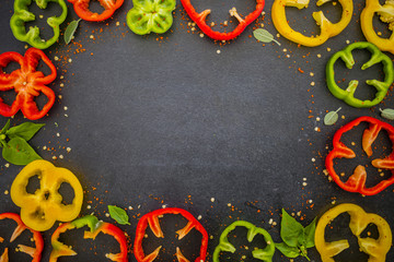 Fresh and raw slices of peppers on a black background. Frame with space for text. 