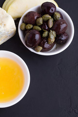 olives, honey and cheese on a black background