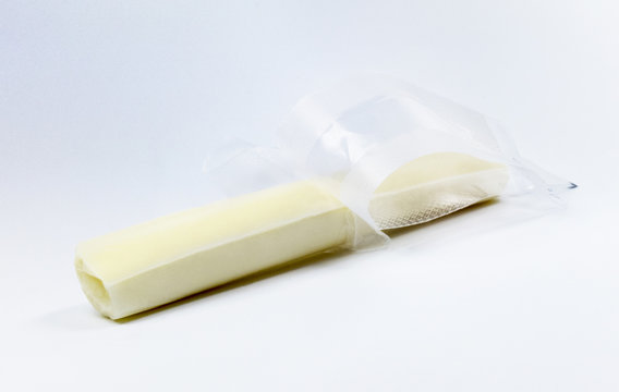 Unwrapped mozzarella string cheese on a light colored background.
