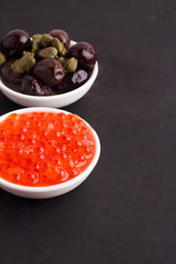 red caviar and olives on a black background