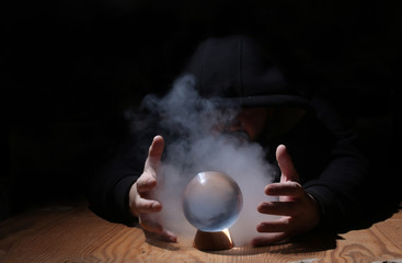 man in a black hood with cristal ball