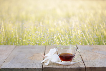 Tea glass and flower on wooden table at outside