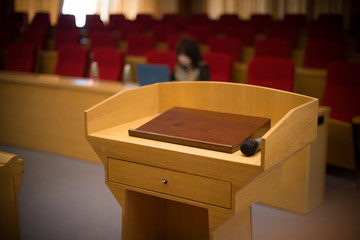 rostrum with a microphone in a reference room with one person at background