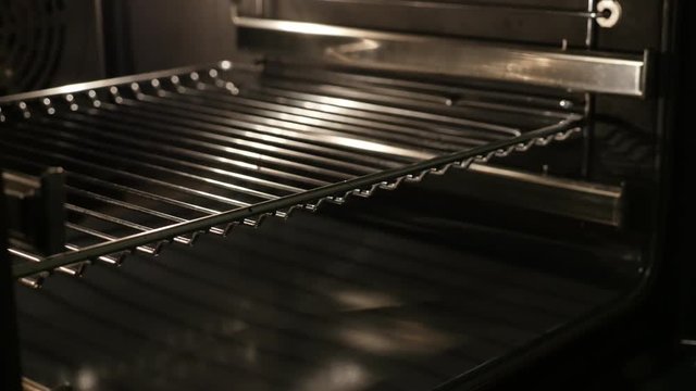 Inside lighted greasy electric oven slow tilt 4K 2160p 30fps UltraHD footage - Close-up of thermally insulated stove components 3840X2160 UHD tilting video 