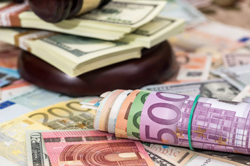 Wooden Law Gavel on Euro and Dollar background.