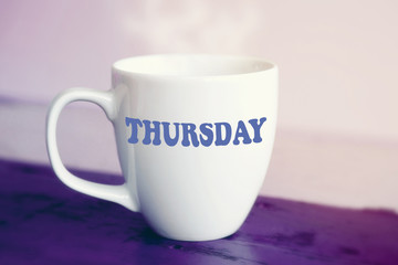 Obraz na płótnie Canvas white cup with the word Thursday on it