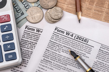 tax form w4  with pen and us dollar, calculator and pen.