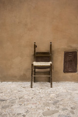 vintage chair a little broken leaning against a wall outside