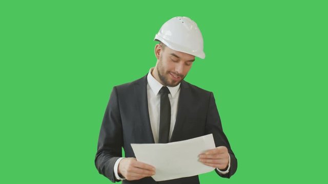 Medium Shot of a Successful Businessman wearing Hard Hat and Browsing through Charts Happily. Shot on a Green Screen Background.  Shot on RED Cinema Camera 4K (UHD). 