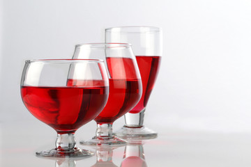 Three Red Wine Glasses on White Reflective Background