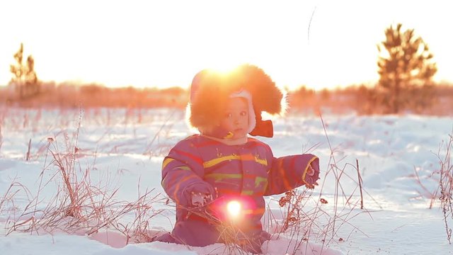 Happy child playing in the snow at sunset.