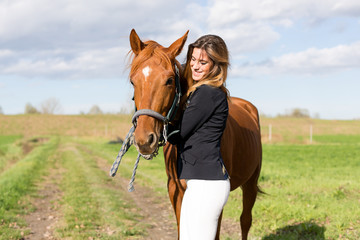 Fototapeta premium Beautiful young girl in uniform competition hugs her horse : outdoors portrait on sunny day