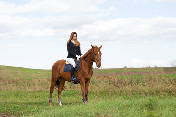 Beautiful young girl in uniform competition ride her brown horse : outdoors portrait on sunny day