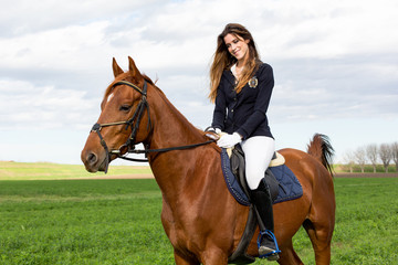 Obraz premium Beautiful young girl in uniform competition rides with safety her brown horse and smiling: outdoors portrait on sunny day