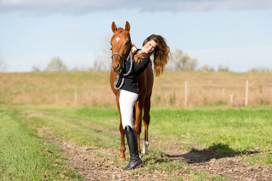 Beautiful young girl in uniform competition hugging her horse : outdoors portrait on sunny day