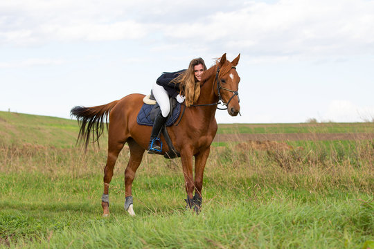 Beautiful young girl in uniform competition ride and stroke her brown horse : outdoors portrait on sunny day