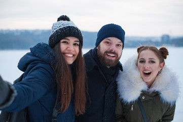 Group of three friends taking selfie photo in winter snow park