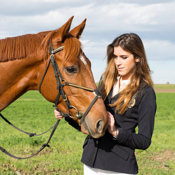 Beautiful young girl in uniform competition hugs her horse : outdoors portrait on sunny day