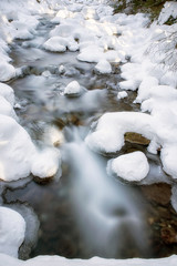 Long exposure of river in winter forest at Jalovecka valley, Slovakia