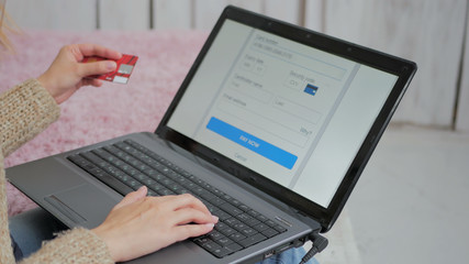 Young woman buying goods from the internet and entering number security code from credit card on laptop. Online, technology and internet concept.