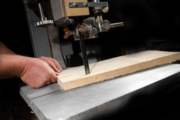 A craftsman cutting a plank of wood with bandsaw