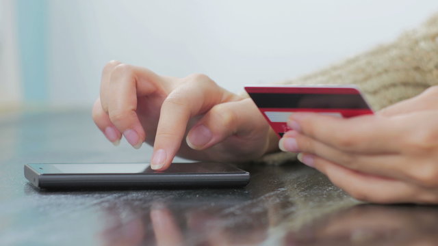 Young woman buying goods from the internet and entering number security code from credit card on smartphone. Online, technology and internet concept