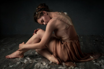 girl dancing barefoot with feathers. ballet. grey background

