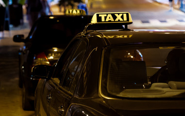 Taxi sign on the roof of a taxi car at night street