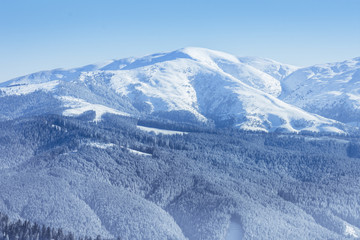 Winter landscape of the mountains and trees covered by snow in Brasov, Romania. View of the Romanian Carpathian Mountains and the forests in the winter season covered by snow