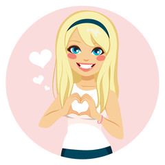 Beautiful blonde girl making heart shape with hands on Saint Valentine day