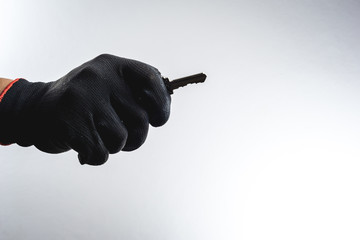 Hand with black grove holding a key