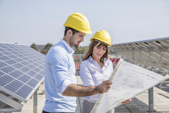 Two architects with blueprint at solar power station