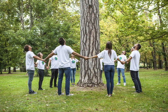 Teenage volunteers standing in circle round tree
