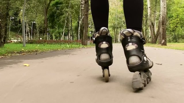 Rollerblading. Close-up shot of female legs in inline skates moving on walking path. Slow motion. HD