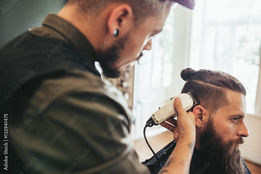 Wall mural hairdresser cutting hair of customer at salon