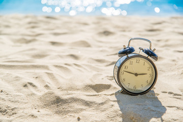 old retro clock on sand beach over blurred of tropical blue sea