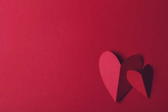Red paper love heart on a plain red background. Valentines day romance background