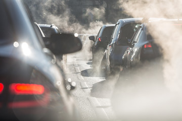 Obraz premium Niewyraźne sylwetki samochodów otoczonych parą z wydechu