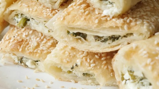 Served on plate filo pie with sesame cheese and spinach slow tilt 4K 2160p 30fps UHD footage - Thin sheets of dough rolls baked with filling close-up 3840X2160 UltraHD tilting video