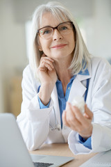 Senior female doctor giving prescription to patient