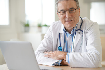 Portrait of senior doctor sitting in medical office