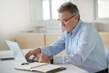 Senior man in office working on laptop computer