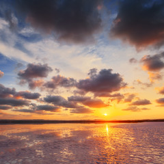 Fototapeta na wymiar Sunset sky with clouds above salt lake. Beautiful sunny landscape.