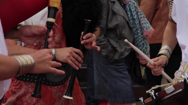 Detalle de las manos de un trio de musicos  disfrazados con ropas de la antigua roma tocando gaitas y tambor o caja de percusion, en espectaculo callejero al aire libre y con gente que pasa