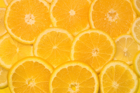 Fresh oranges and lemons background. Yellow food background. Juicy slices of orange and lemon. Top view