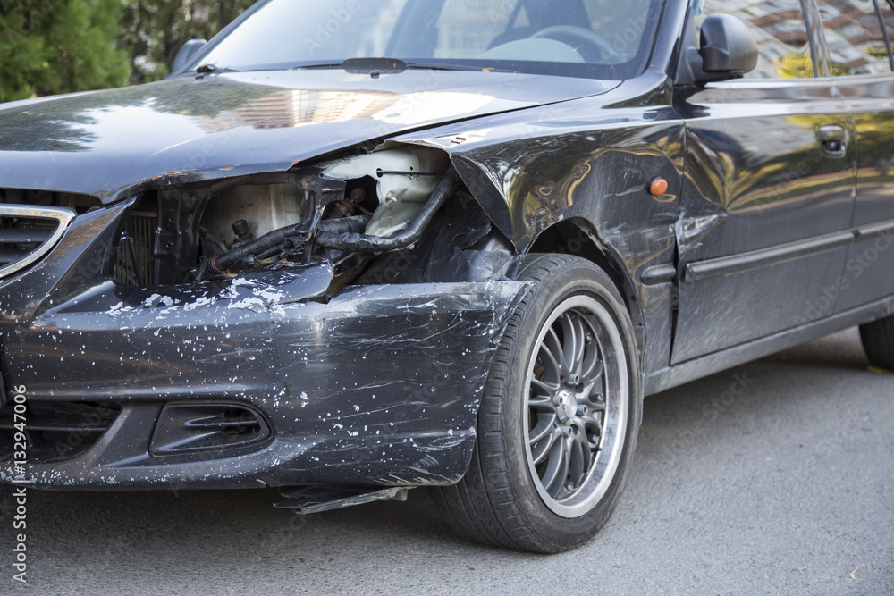 Wall mural Small black car with damaged headlamp after collision